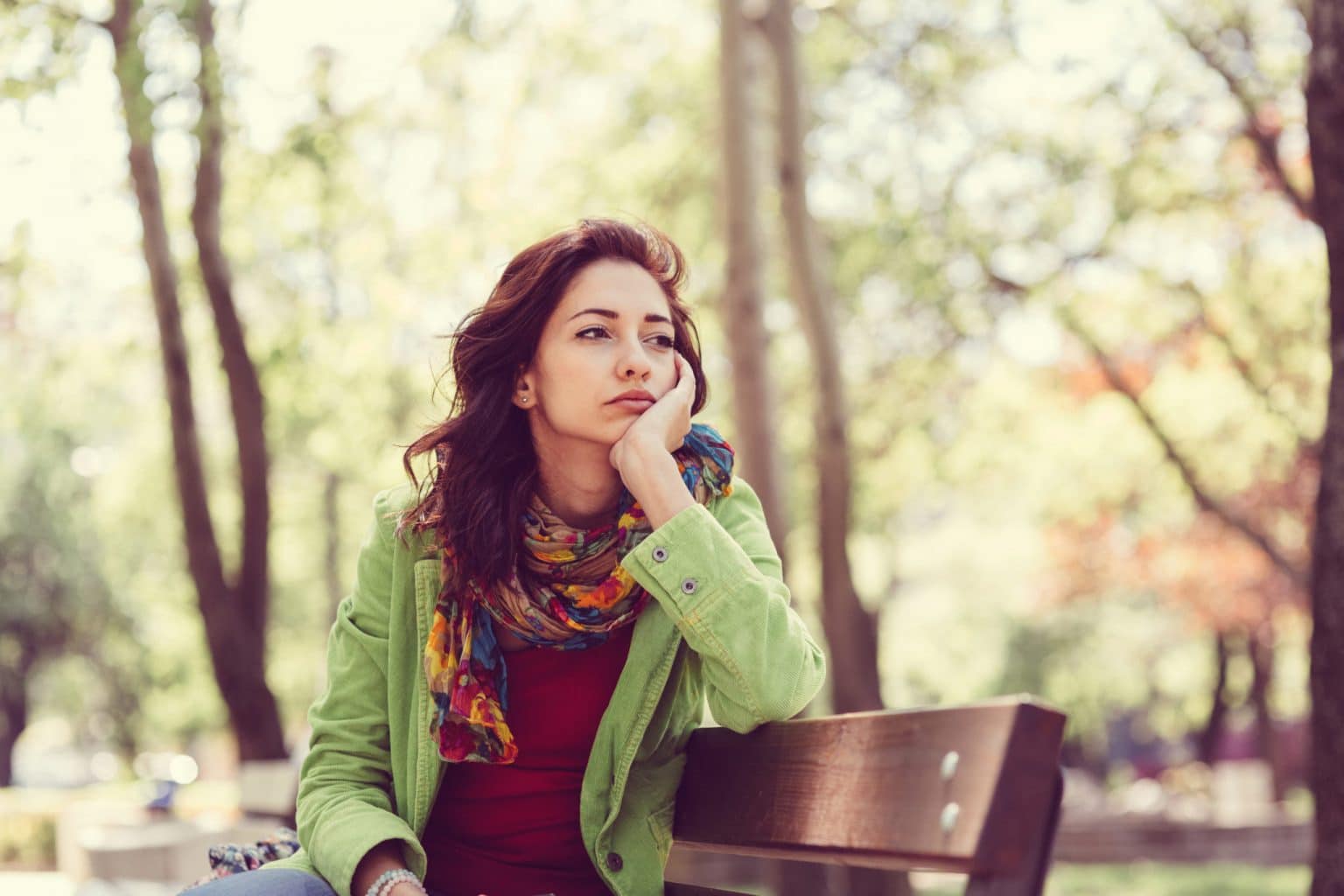 Woman sitting on a park bench with an uninterested expression because she can't smell anything.