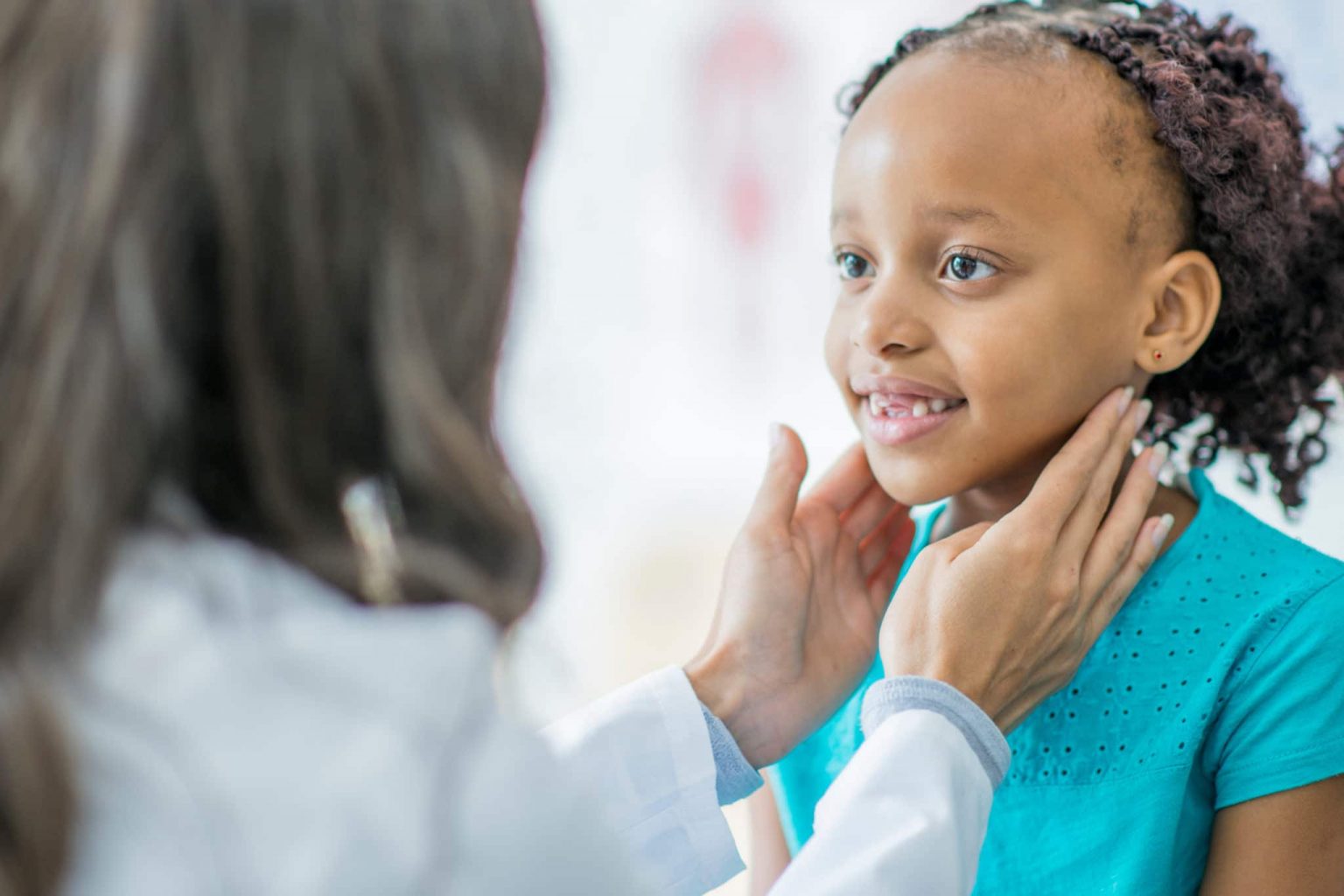 Otolaryngologist examining a young patient's neck for signs of tonsil infection.