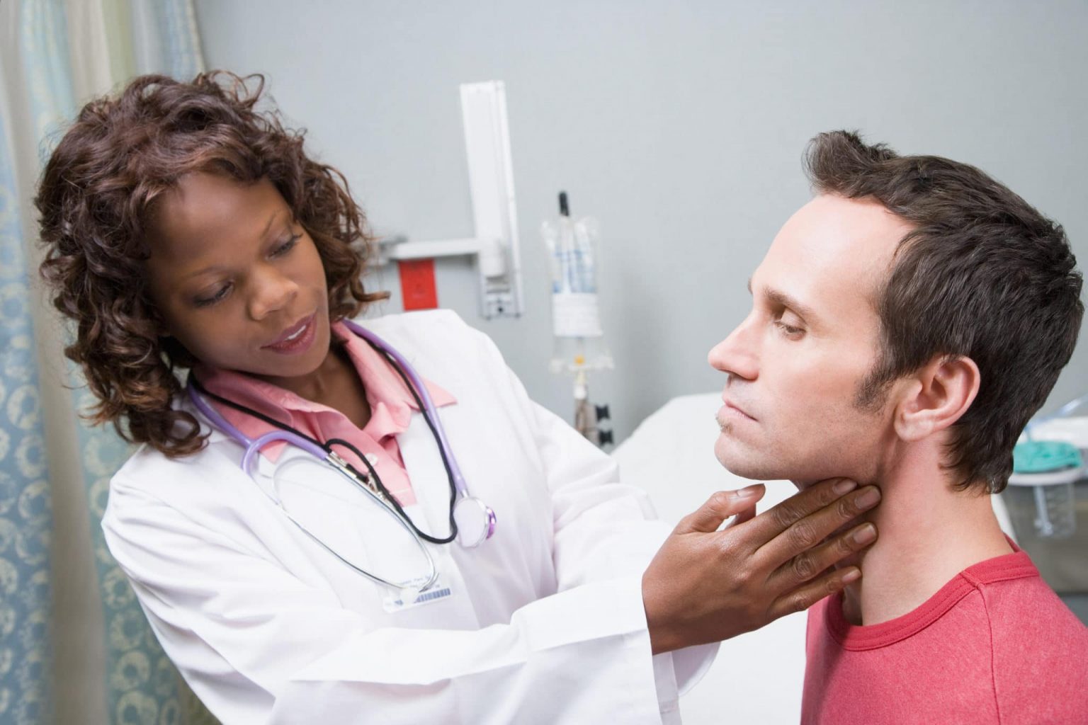 Female doctor examines the outside of a male patient's throat.