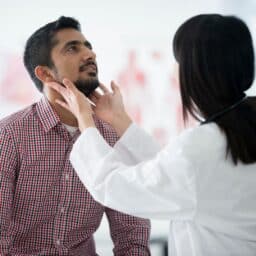 doctor checking persons throat