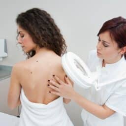 Doctor looking at moles on a woman's back