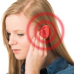 Woman with tinnitus holding her ear. 