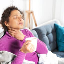 Woman sips tea with sore throat