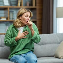 Coughing woman holding her chest