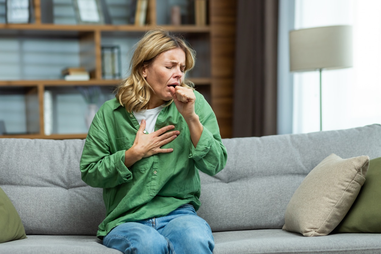 Coughing woman holding her chest.