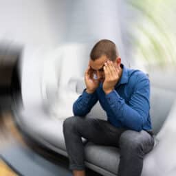 Man with vertigo sitting on the couch, head spinning