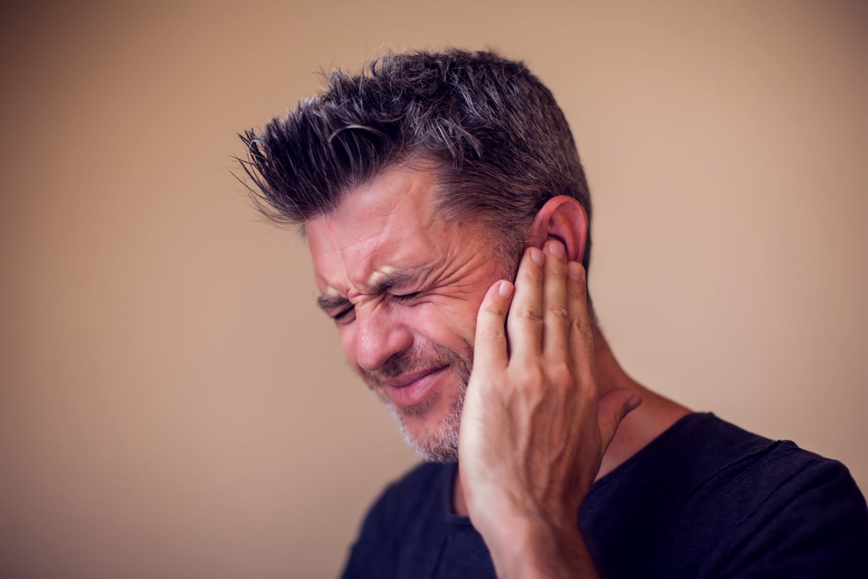 Man with ear pain holding his ear.