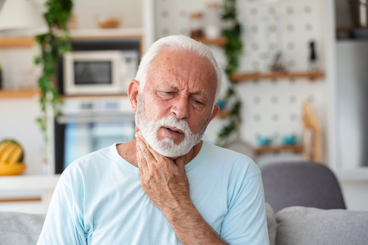 Senior man holding his sore throat.