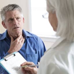 Senior man with a sore throat talking to his doctor