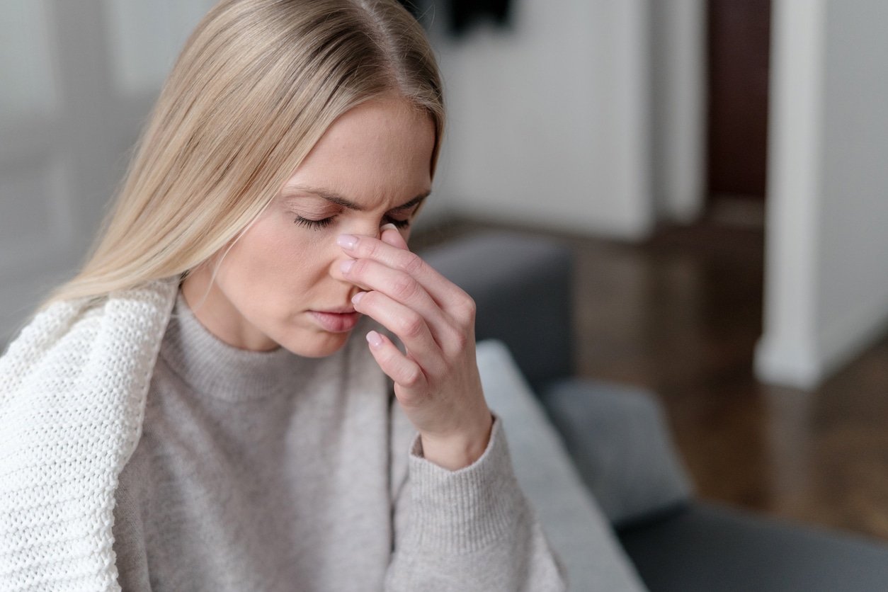 Woman holding her congested nose.