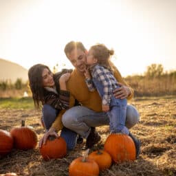 Family harvesting pumpkins in autumn field